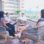 Business team having a casual meeting on a rooftop terrace with a cityscape view.